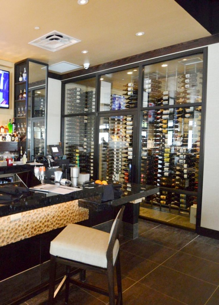 This contemporary commercial custom wine cellar in Miami, florida, displays the wines in metal wine racks.