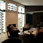 The modern wine cellar lighting adds to the mood and highlights the beautiful bottles behind the glass door.